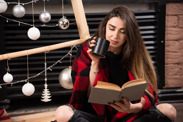Woman enjoying book with warm coffee indoors